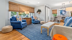 Un salon moderne avec un canapé bleu, une table basse en bois et une grande fenêtre équipée de stores.