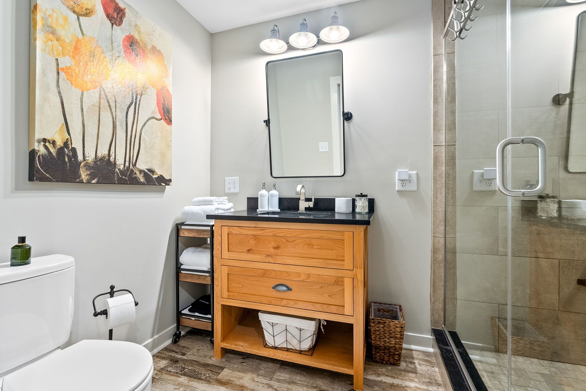 Un baño moderno con tocador de madera, un espejo grande y una cabina de ducha de vidrio.
