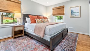 Une chambre à coucher avec un lit, une table de chevet et une fenêtre équipée de stores.