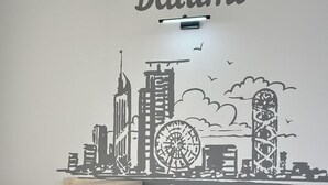 Ein Zimmer mit Stadtbild-Wandkunst, einem grünen 'C'-Logo und einem gepolsterten Ledersessel.