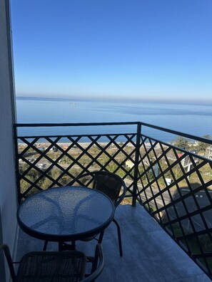 Un balcón con vista al mar, una mesa redonda y dos sillas.
