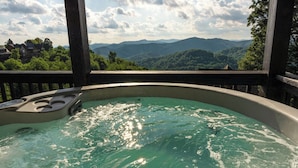 Un jacuzzi con vistas a montañas y una terraza de madera.