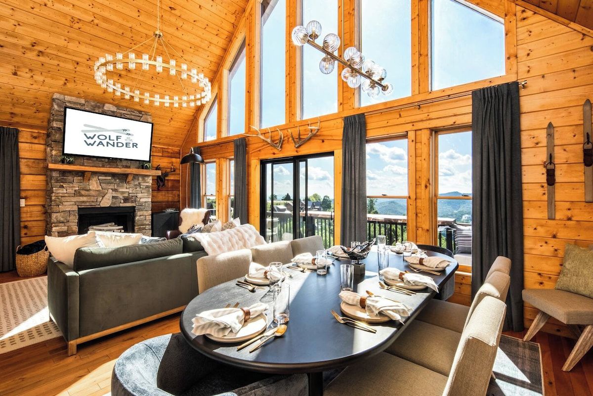 Un salon spacieux avec une cheminée, une grande table à manger dressée pour le repas et un coin salon confortable.