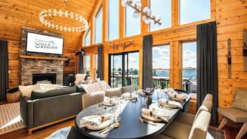 Un salon spacieux avec une cheminée, une grande table à manger dressée pour le repas et un coin salon confortable.