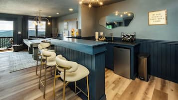 Une cuisine moderne avec un coin bar, des tabourets de bar, un évier et un miroir.