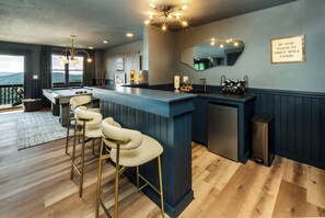 Eine moderne Küche mit Bar, Barhocker, Spüle und Spiegel.