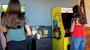 Two individuals playing arcade games in a room with a wooden floor and a wall-mounted TV. - 4,300ft Mountain Chalet - Sauna & Views (Mars Hill)