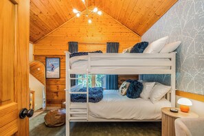 Ein Schlafraum mit Etagenbetten, Holzboden und einem gerahmten Bild an der Wand.