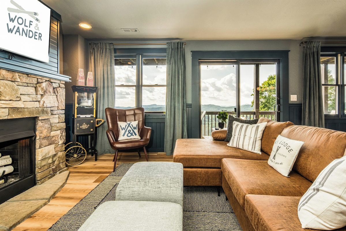 A cozy living room with a stone fireplace, a leather sofa, and a view of the outdoors.