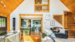 A spacious living area with a high ceiling, wooden beams, a dining table, and a cozy seating arrangement. - 4,300ft Mountain Chalet - Sauna & Views (Mars Hill)