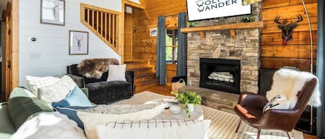 Una sala de estar acogedora con chimenea, un sofá cómodo y un televisor montado encima.