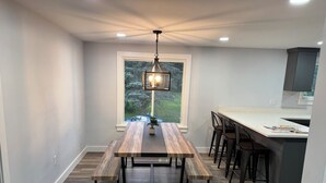 Une cuisine moderne avec une table à manger en bois, des bancs et des tabourets de bar.