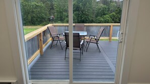 Une terrasse avec une table et des chaises, une rambarde et une vue sur une zone boisée.