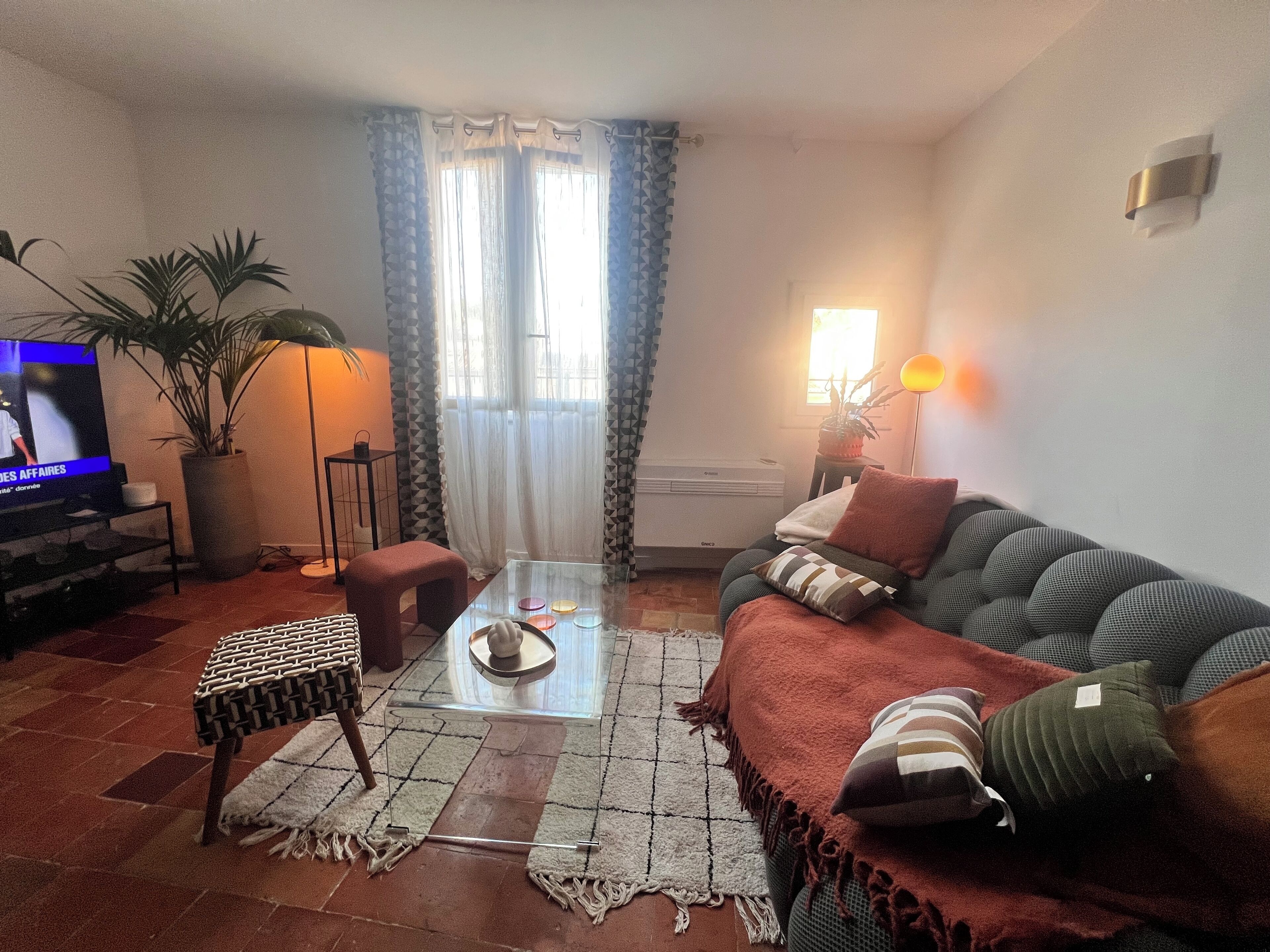 A living room with a sofa, a coffee table, a TV, a plant, and a lamp.
