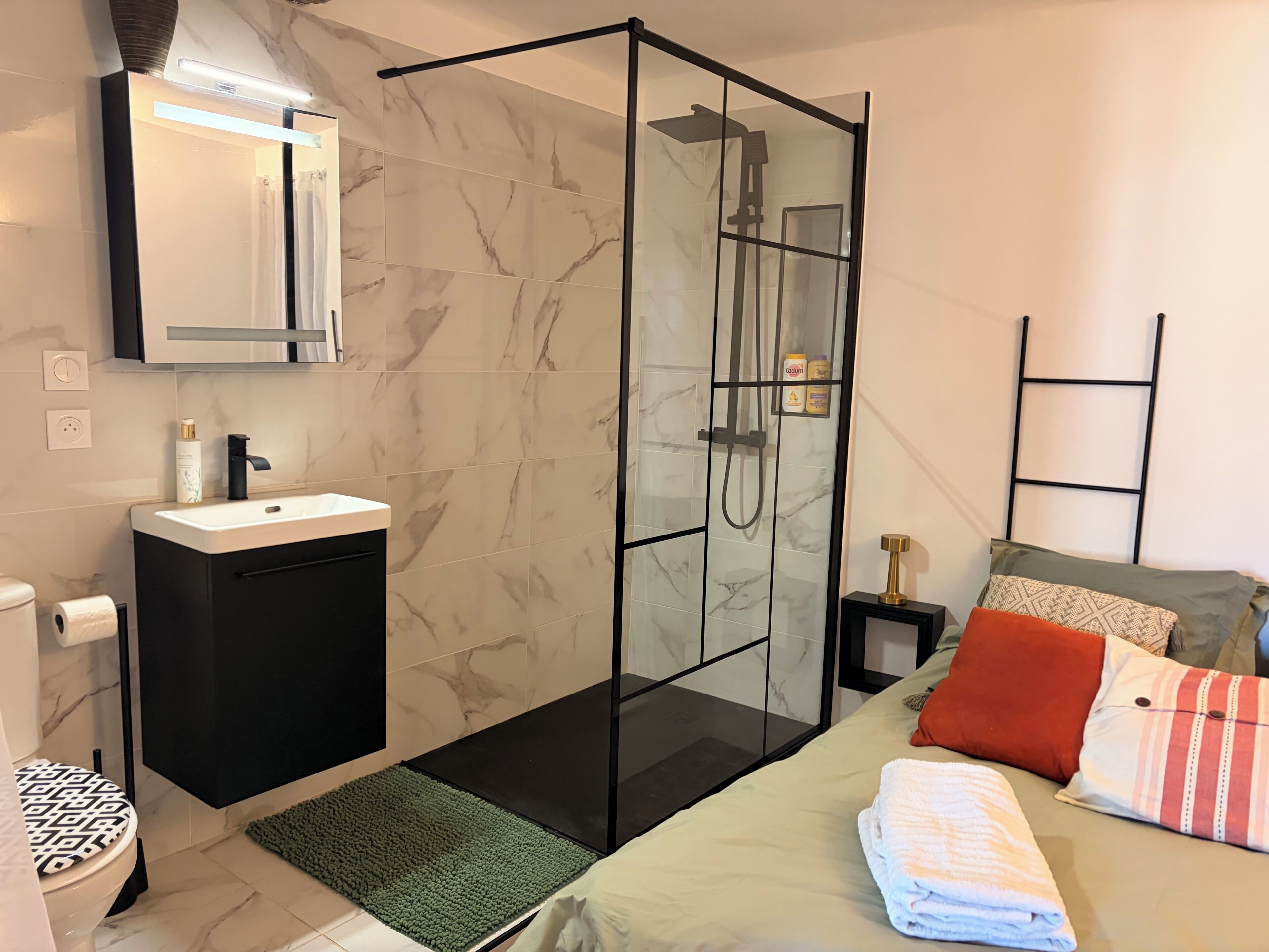 A modern bathroom with a glass shower enclosure, a sink with a marble countertop, and a toilet with a patterned seat.