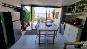 A modern kitchen with a dining area, large windows, and a view of the marina. - Facing the port, lovely studio on raised ground floor with large terrace, panoramic view (Bandol)
