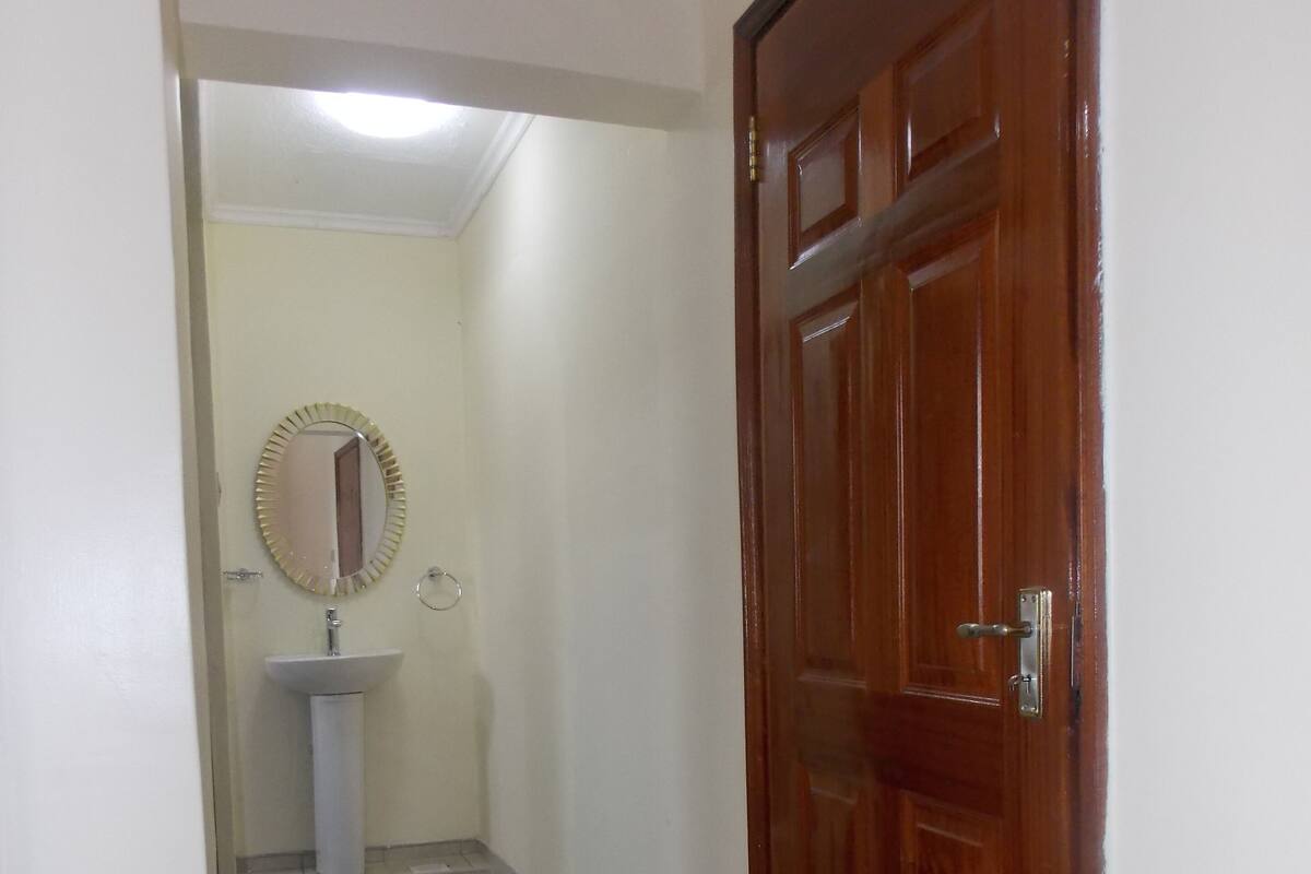 A hallway with a wooden door, a white sink, and a mirror.