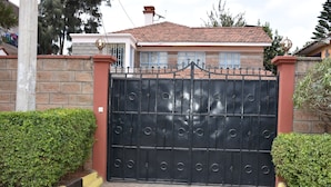 A gated entrance with a metal gate, brick walls, and a tiled roof.