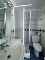 Un baño con un lavabo blanco, un inodoro y una cabina de ducha.
