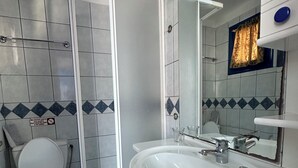 A bathroom with a white toilet, a sink, and a shower enclosure. - Galini Hellenic Hospitality (Alonissos)