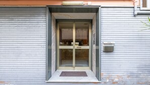 A modern building entrance with a glass door, a small step, and a mailbox on the wall.