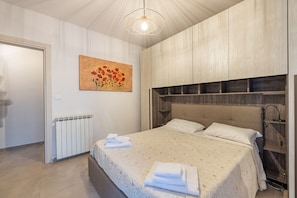 Una camera da letto con un letto, un termosifone, un quadro e una testiera in legno.