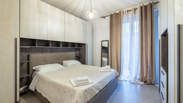 A bedroom with a large bed, a wardrobe, a mirror, and a ceiling light.