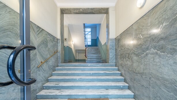 Una escalera de mármol con barandilla, que lleva a una plataforma con vista al cielo azul.