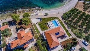 Vista aérea de una zona residencial costera con casas, una piscina azul cristalina y una playa.