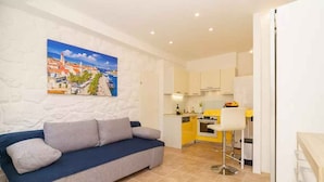 A modern living room with a sofa and a painting of a coastal town. - Studio with air conditioning and barbecue facilities (Crikvenica)