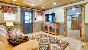 Una habitación acogedora con techo de madera, una puerta negra, cómoda de madera y una alfombra estampada.