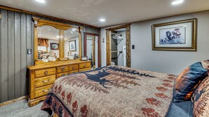 Une chambre à coucher avec un grand lit, une commode en bois, un miroir et un tableau encadré accroché au mur.
