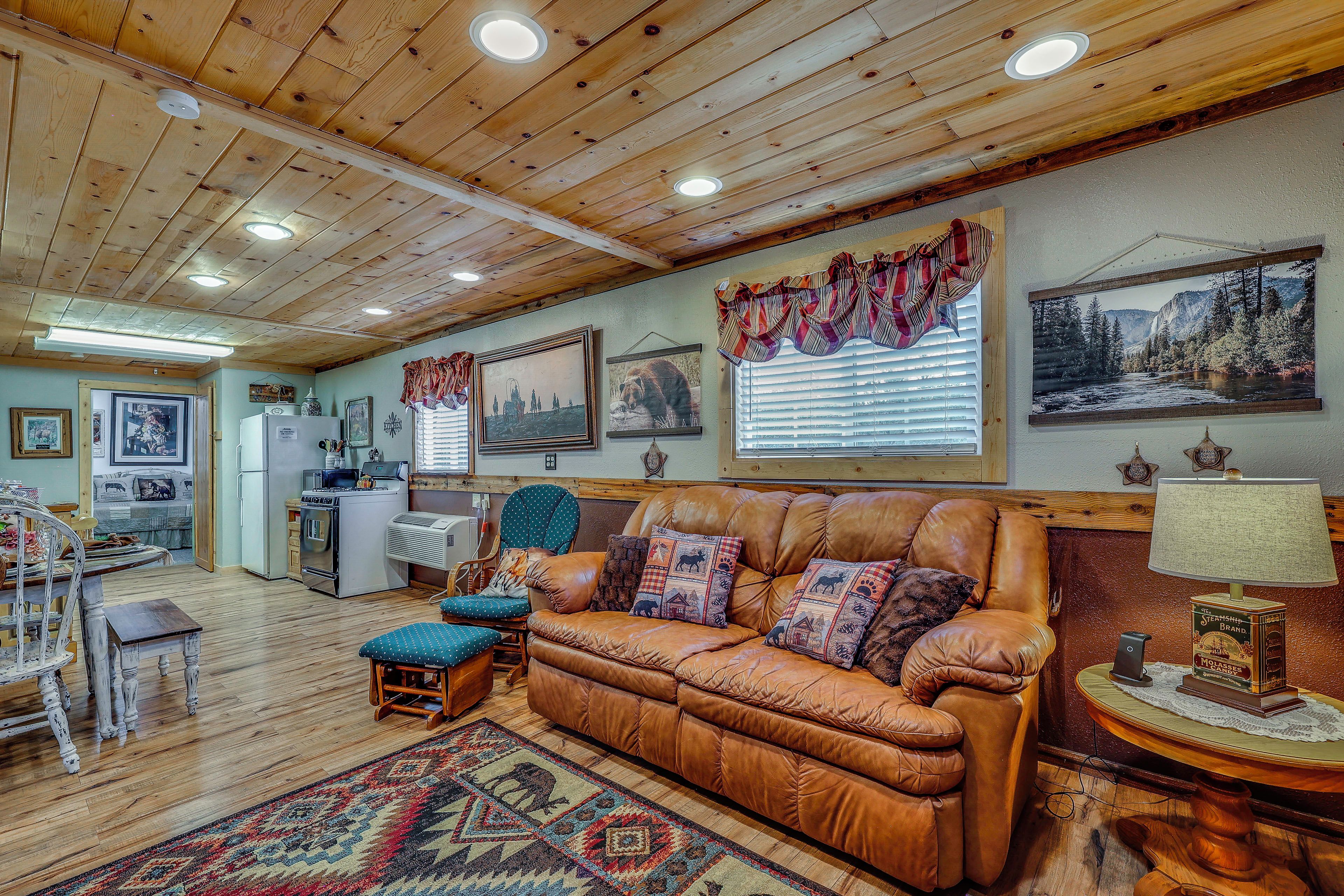 A cozy living room with a leather sofa, a patterned rug, and a dining area with a table and chairs.