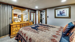 Une chambre à coucher avec un grand lit, une commode, un miroir et un tableau encadré accroché au mur.
