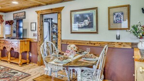 Un coin repas avec un plafond en bois, une table dressée pour quatre personnes et un banc.