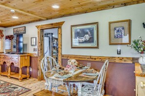 Un coin repas avec un plafond en bois, une table dressée pour quatre personnes et un banc.