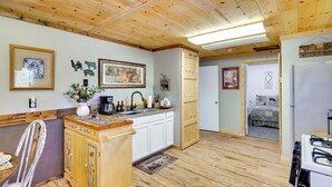 Una cocina con armarios de madera, un lavamanos y una zona de comedor con una silla y una mesa.