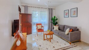 Una sala de estar con sofá, mesa de centro, sillón, planta en maceta y aparador de madera.