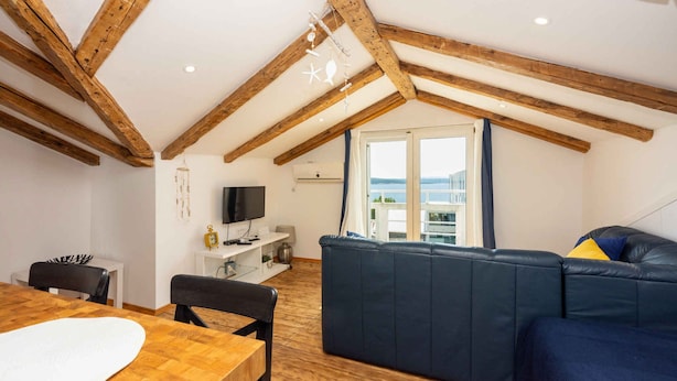 Un salon chaleureux avec un plafond en bois, un canapé bleu, une table à manger et un téléviseur.