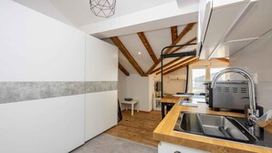Une cuisine moderne avec un plafond en bois, des armoires blanches et un évier en acier inoxydable.