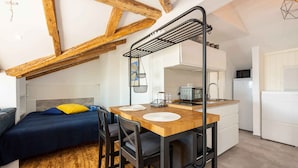 Une cuisine de taille réduite, avec une table en bois, deux chaises, un four à micro-ondes et un évier.