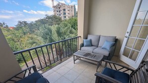 A balcony with a sofa, chairs, and a table.