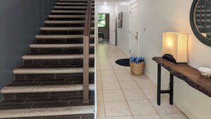 A staircase leading to a landing with a wall-mounted light fixture and a basket on the floor.