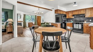 A modern kitchen with wooden cabinets, a black refrigerator, and a dining area with a wooden table and chairs. - Modern Mountain Calm – Oakhurst Home by Yosemite (Oakhurst)