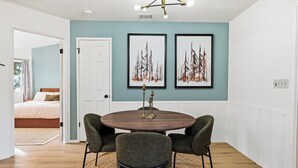 A dining area with a round table, four chairs, and two framed artworks on the wall. - Yosemite Getaway! Stylish 2BR near south gate (Oakhurst)