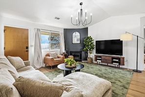 A modern living room with a sectional sofa, a fireplace, a television, and a large plant.