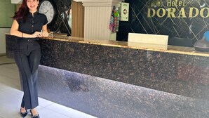 En hotelreception med et ur, et skilt der angiver et førstehjælpsrum, og en receptionsdisk.
