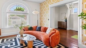 A cozy living room with a curved orange sofa, a round coffee table, and a patterned rug.