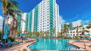 A hotel with a large pool, palm trees, and multiple high-rise buildings. - Condo w/2 Queen beds and Ocean View | Tides (Hollywood)
