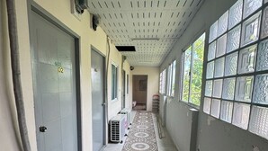 A hallway with patterned tile flooring, a ceiling with ventilation, and a window with decorative glass panels. - Sukhum Mega Bangna Guest House By Zuzu (Bangkok)